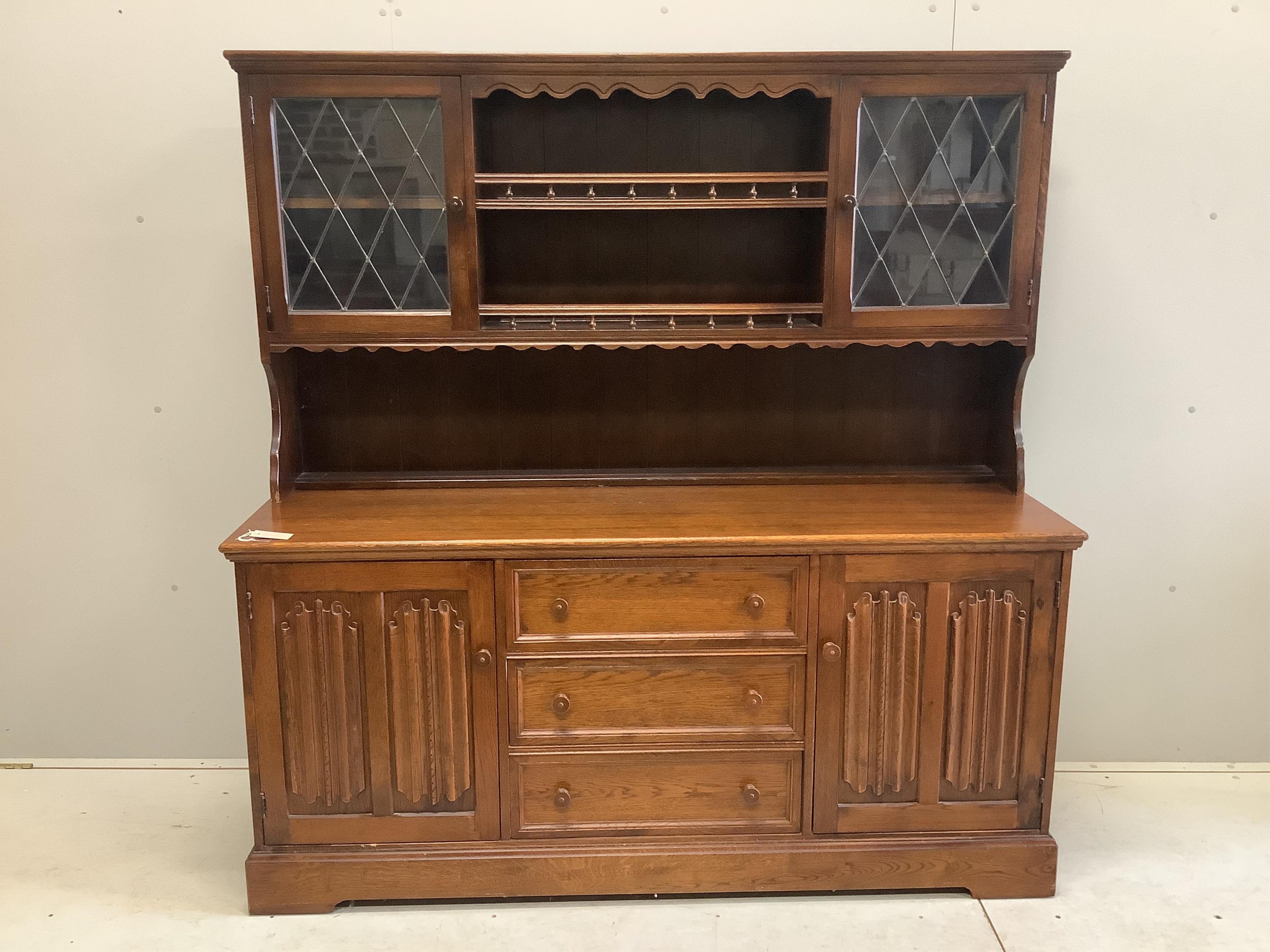 A reproduction oak dresser, the cupboards with linen fold carved fronts, width 160cm, 48cm, height 164cm. Condition - fair to good